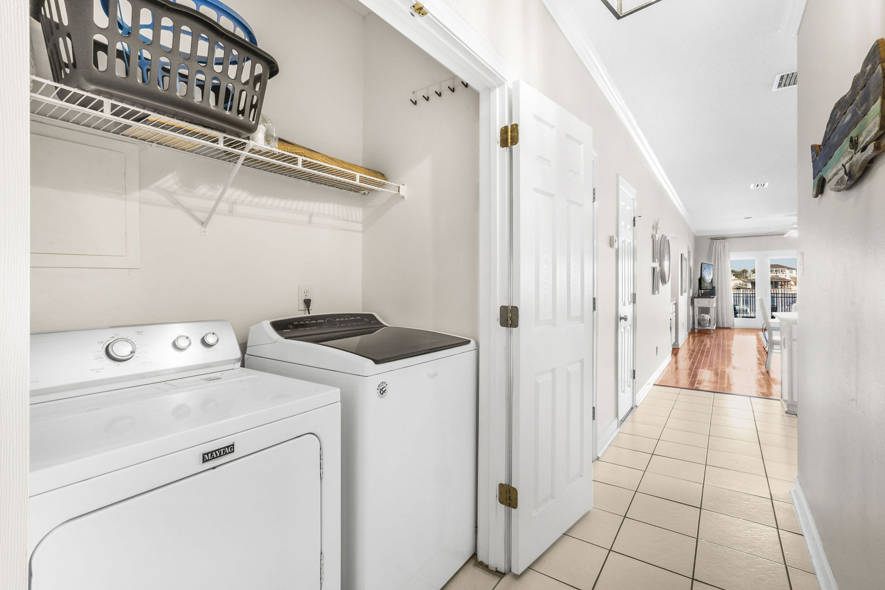 A laundry room with a washing machine, dryer, and a basket on a shelf.