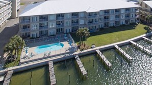 A multi-story hotel with a pool area, including a deck and a water feature. - Dolphin Harbor 1B Bay Beach Access Sleeps 10 Three Bedrooms 3 Baths (Orange Beach)