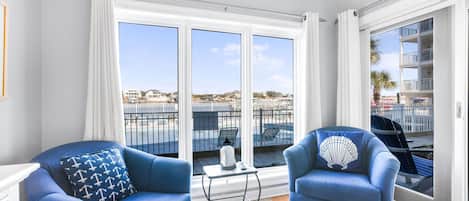 A balcony with two blue armchairs, a small table, and a view of a marina.