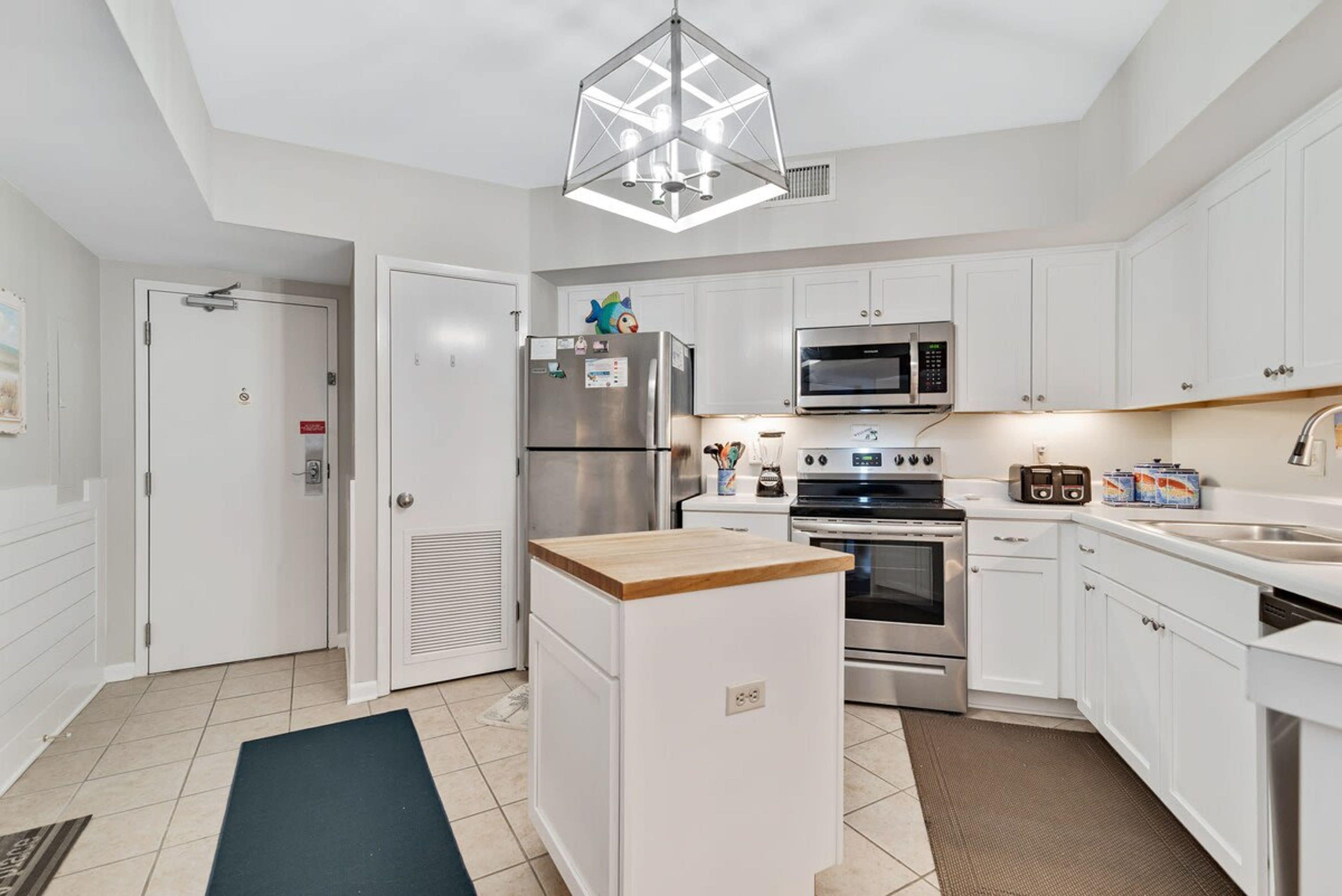 A modern kitchen with white cabinets, stainless steel appliances, and a wooden island.