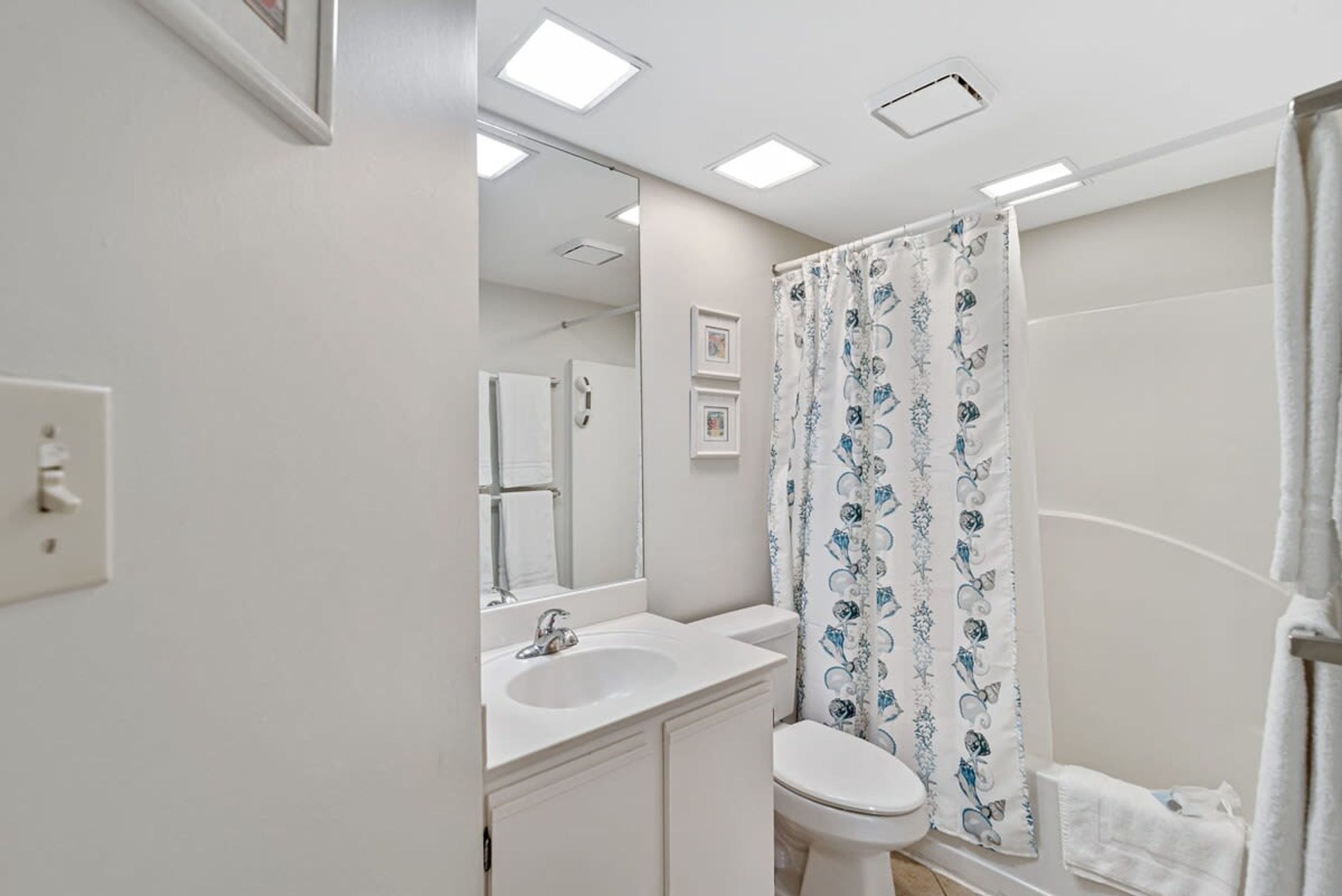A bathroom with a white sink, toilet, and shower curtain.