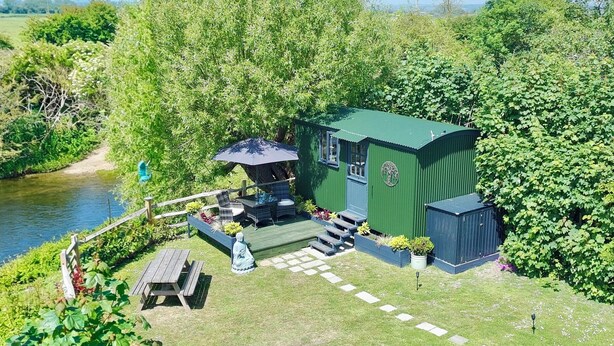 Une maison verte avec un patio, une petite piscine et un jardin.