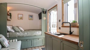 Une petite chambre comprenant un lit, une kitchenette et une fenêtre.