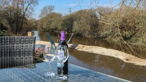 Une bouteille de vin et deux verres sur une table près d’une rivière.