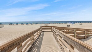A wooden boardwalk leading to a sandy beach with umbrellas and beachgoers. - Phoenix II 2101 3 Bedrooms Amenities Galore Beachfront (Orange Beach)