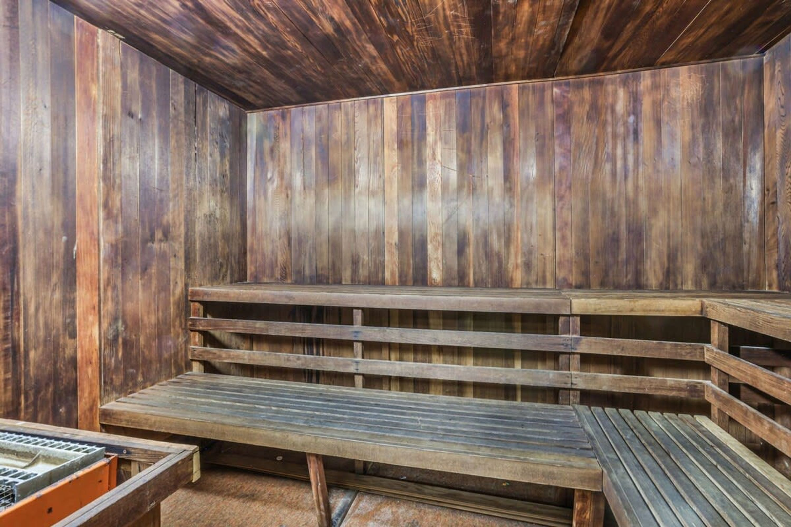 A sauna with wooden benches and a bench with a metal frame.