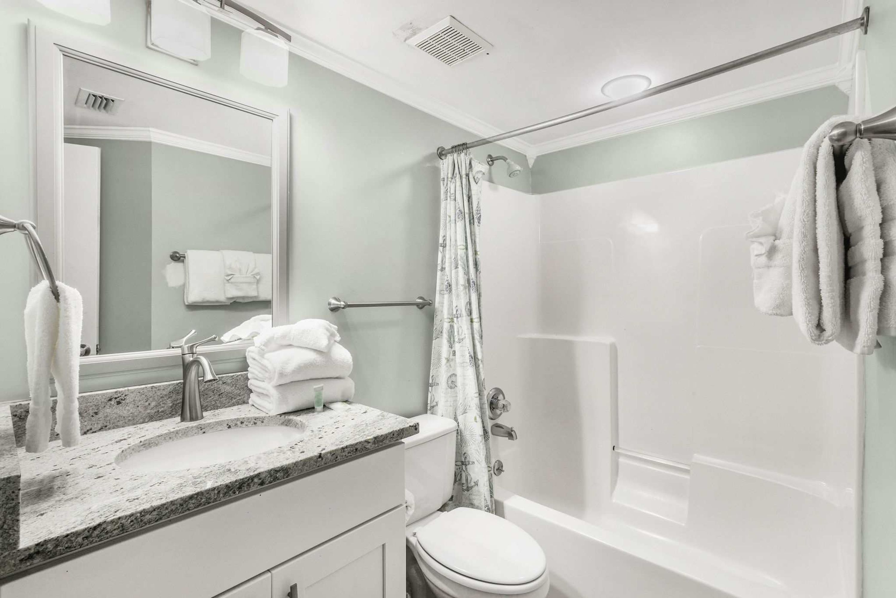 A bathroom with a shower, toilet, sink, and a towel rack.