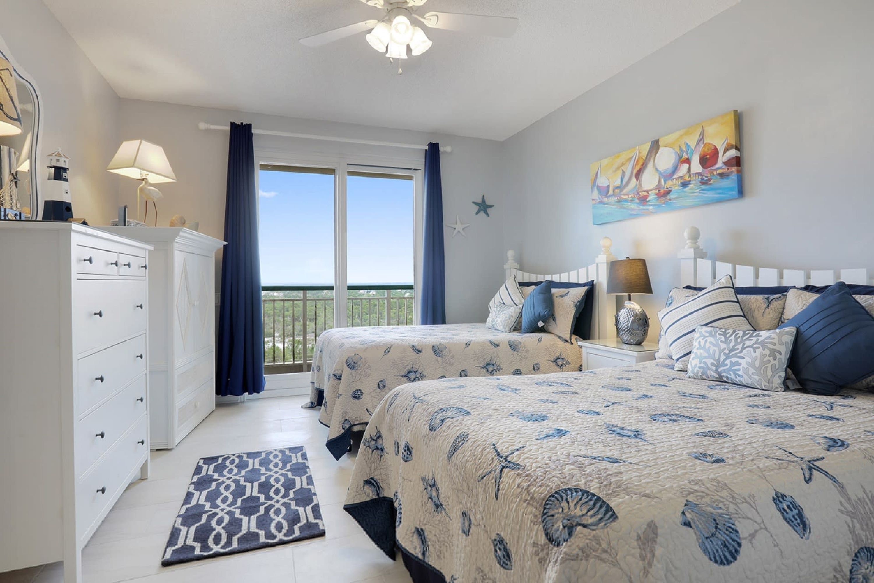 A bedroom with two beds, a dresser, a nightstand, a painting, and a view of the outdoors.