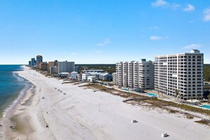 Ein Strandhotel mit mehreren Hochhäusern, einem Sandstrand und blauem Himmel.