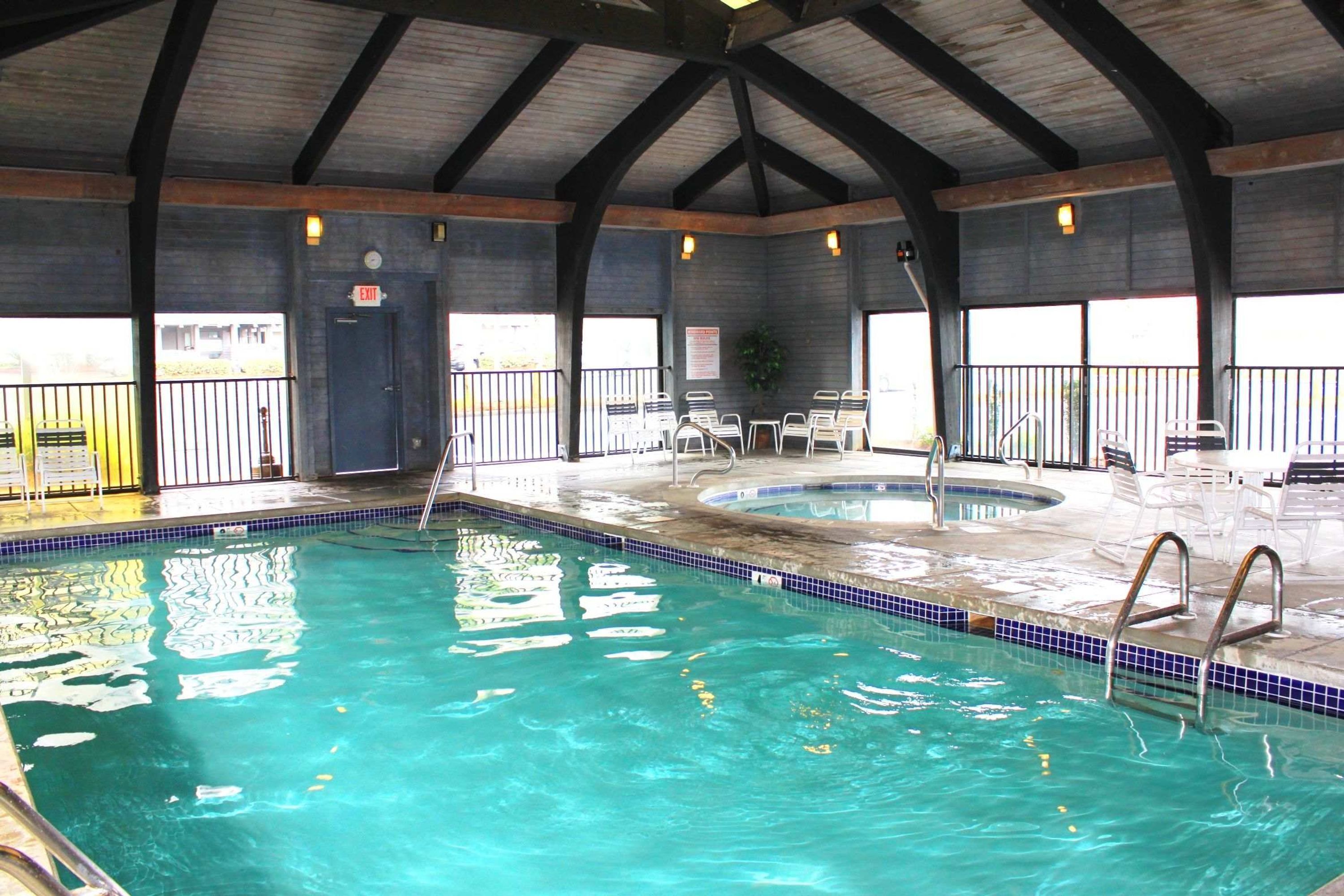 Una piscina interior amb aigua cristal·lina, vora de rajoles blaves i una estructura de teulat coberta.