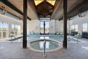 Ein Hallenbad mit Holzbalkendecke und großen Fenstern.