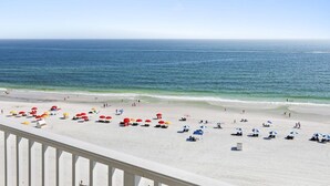 Une plage de sable blanc, avec une eau d’un bleu limpide et des parasols.
