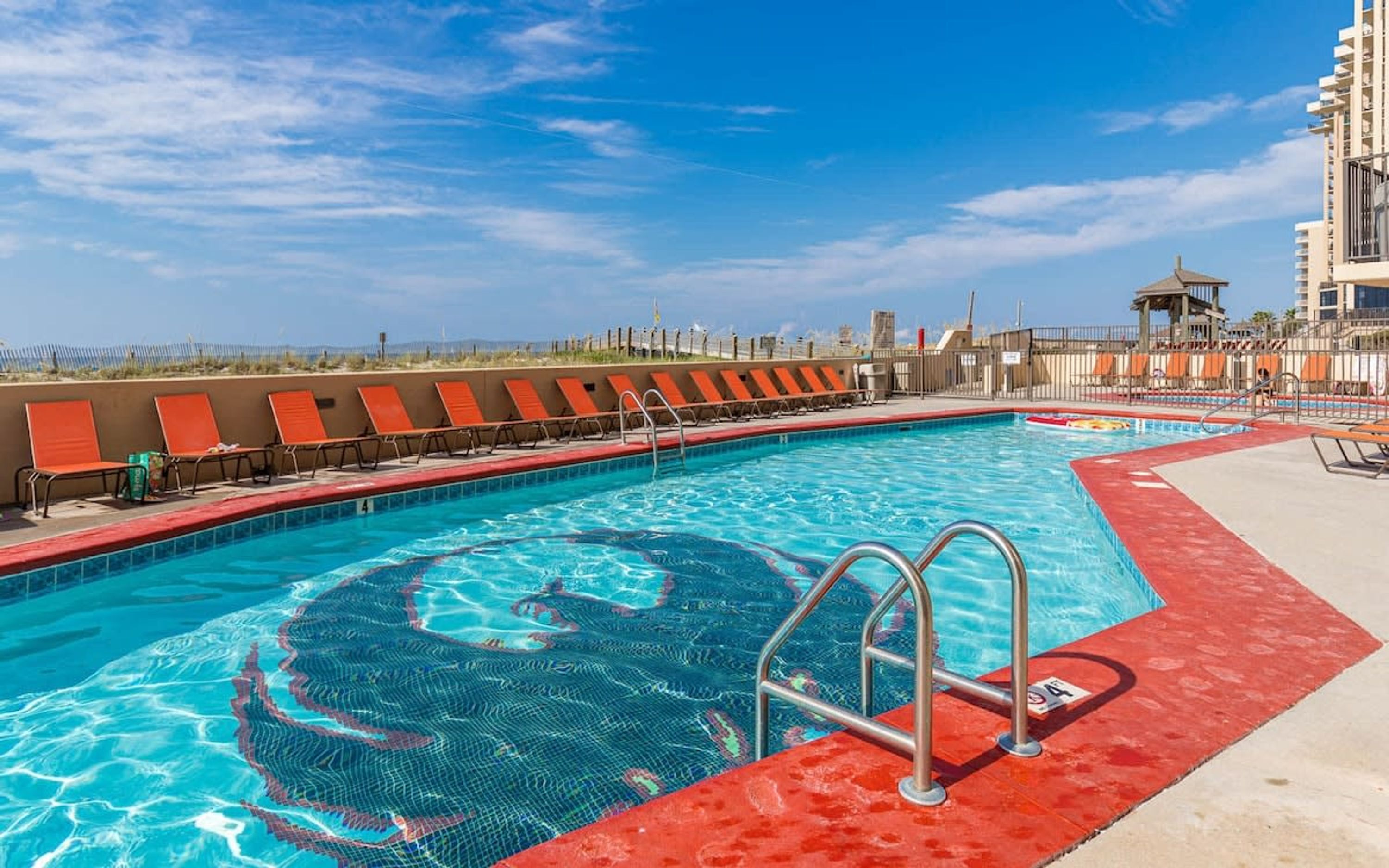 A swimming pool with a red border, multiple lanes, and a lifeguard stand.