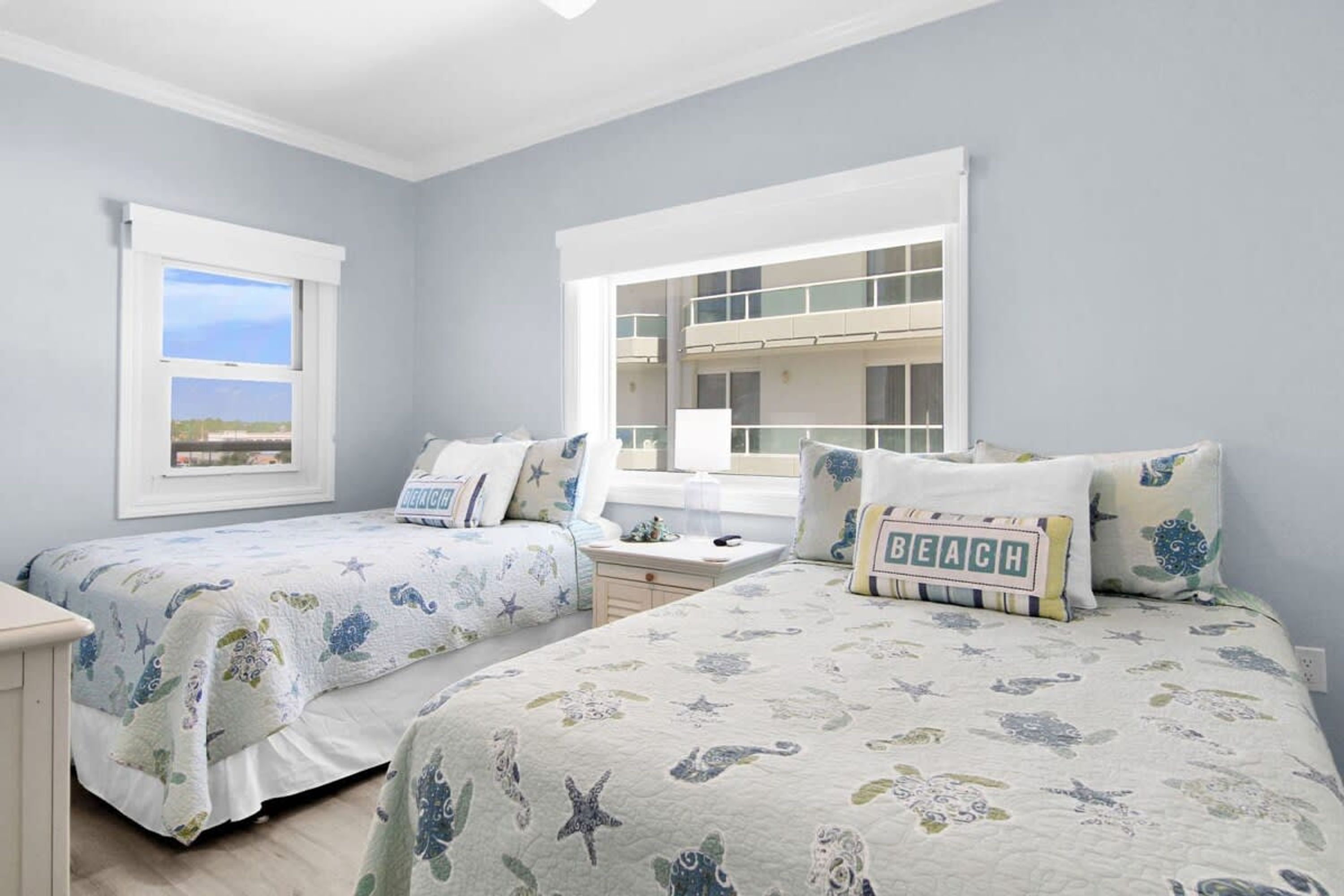 A bedroom with two beds, a window with a view, and a balcony.