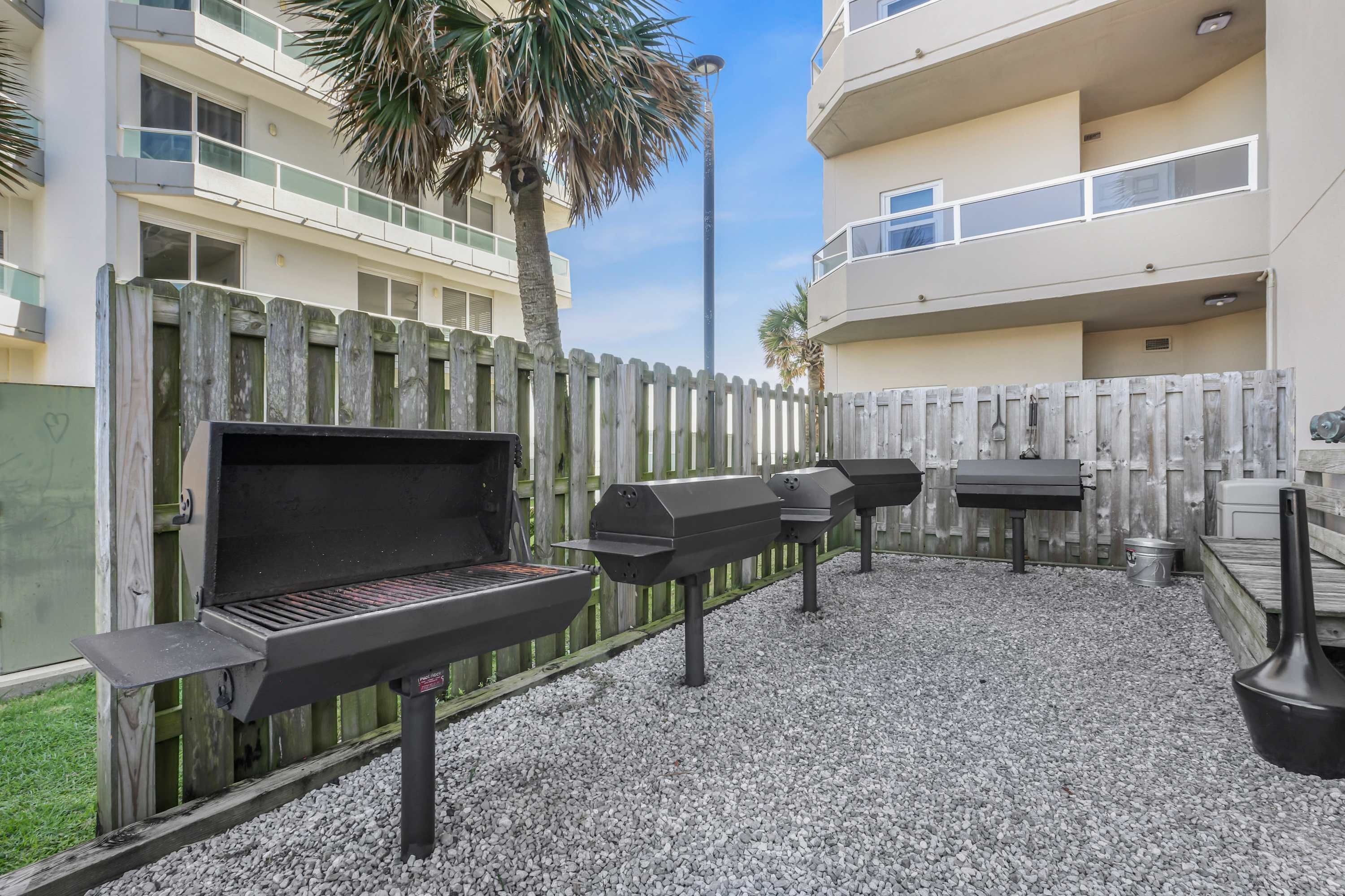 Un jardin avec un barbecue, une table et une poubelle.