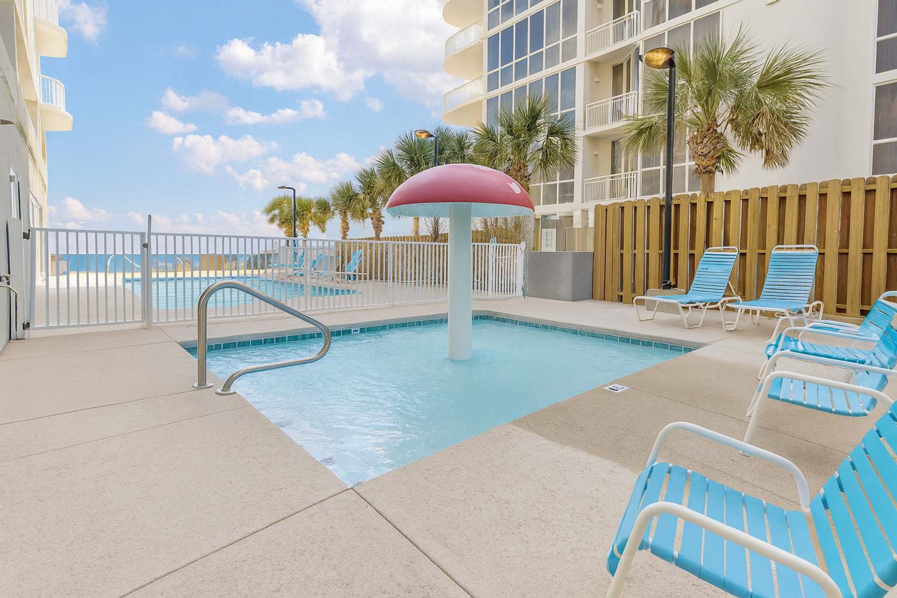 A pool area with lounge chairs and a palm tree.