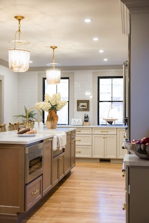 A kitchen with wooden cabinets, a large island, and pendant lights. - The Mermaid Suite Luxury Suite Steps From Thames (Newport)