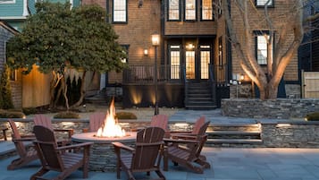 A patio with Adirondack chairs and a fire pit, surrounded by stone walls and a wooden deck.