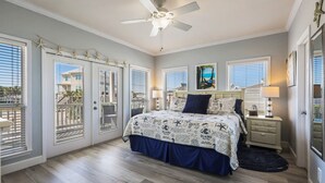 A bedroom with a bed, ceiling fan, and large windows. - Bama Barefoot Beach House- Near Beach Pool (Gulf Shores)