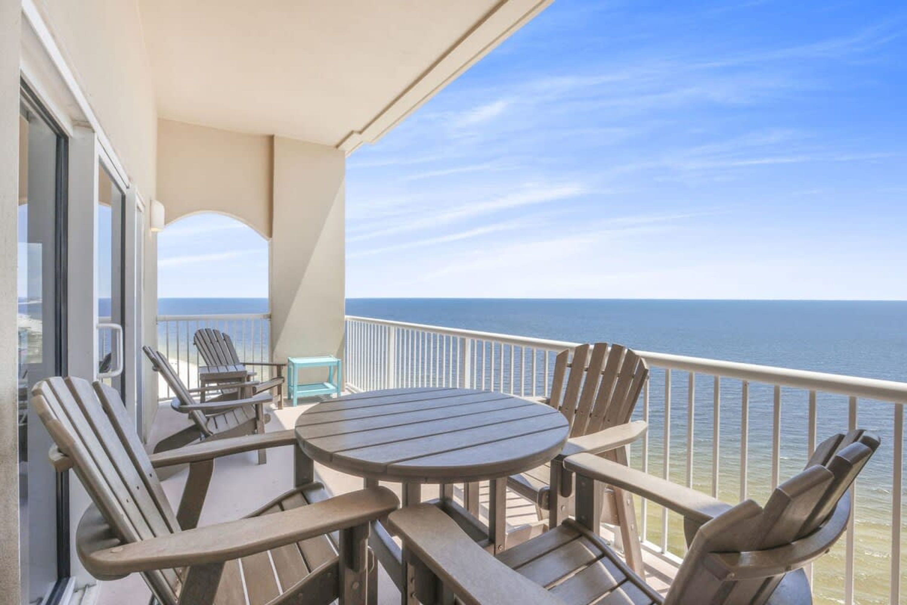 A balcony with a round table and chairs, overlooking a body of water.