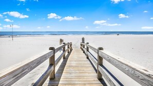 Un paseo marítimo de madera que conduce a una playa con cielo despejado.