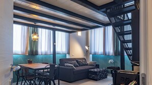A modern living room with a sofa, dining table, chairs, and a staircase. - Milan Central Station - Green Loft (Milano)