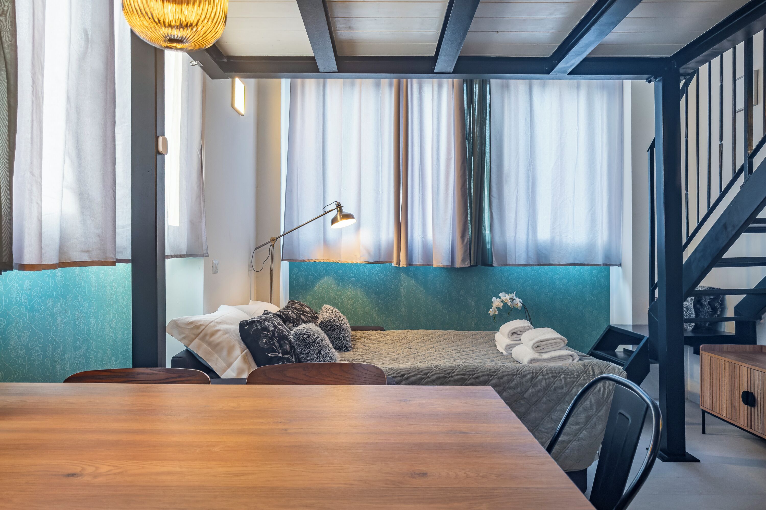 Een moderne slaapkamer met een houten bed, een bureau en een trap.