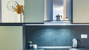 A modern kitchen with a built-in stove, a coffee maker, and a kettle on the counter. - Milan Central Station - Green Loft (Milano)