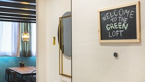 A door with a sign reading "WELCOME TO THE GREEN LOFT" and a view of a dining area with a table and chairs. - Milan Central Station - Green Loft (Milano)