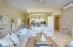 A modern living room with a sofa, coffee table, and a kitchen in the background. - The Beach View Playabonita Beachfront Pool (Las Terrenas)