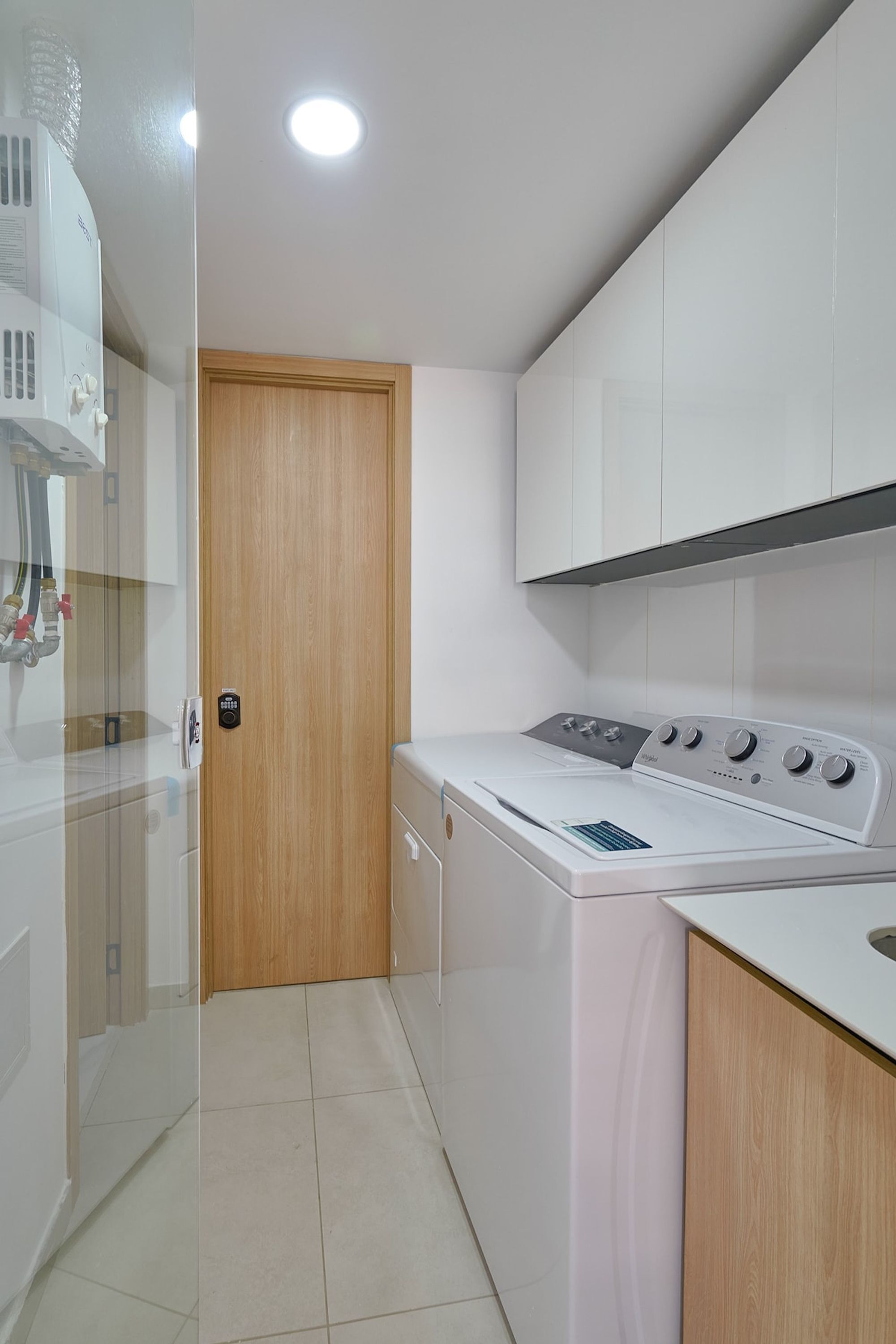 Un lavadero moderno con lavadora, secadora y una puerta de madera.