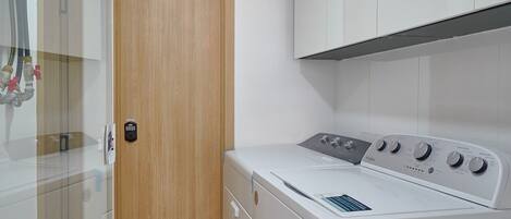 Un lavadero moderno con lavadora, secadora y una puerta de madera.