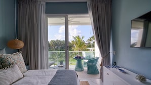 Une chambre à coucher avec un lit, un bureau, une chaise et un balcon donnant sur des palmiers.