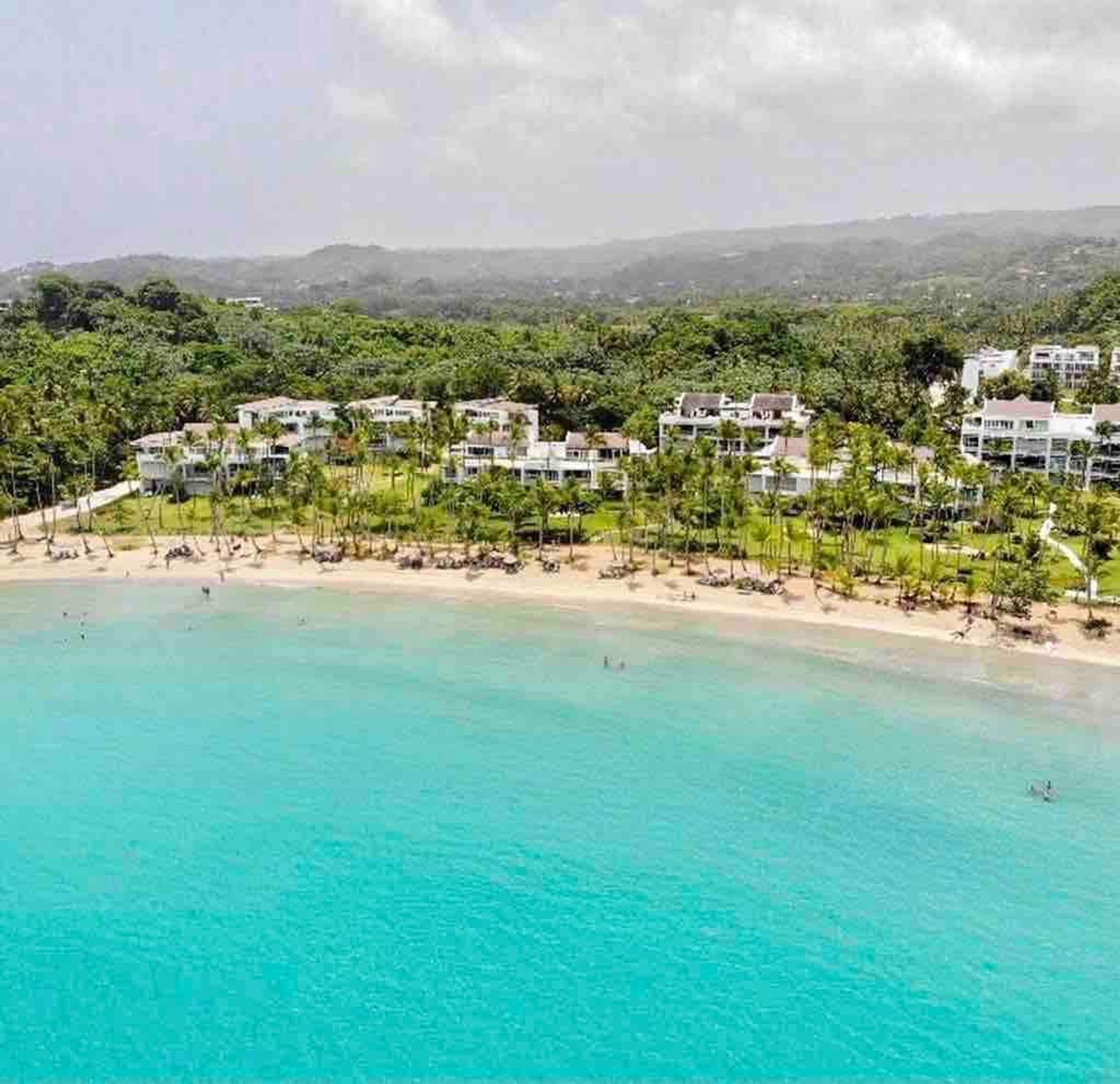 A coastal resort with beachfront villas, a sandy beach, and lush greenery.