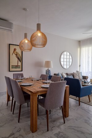 Comedor con una mesa de madera, sillas grises y lámparas colgantes.
