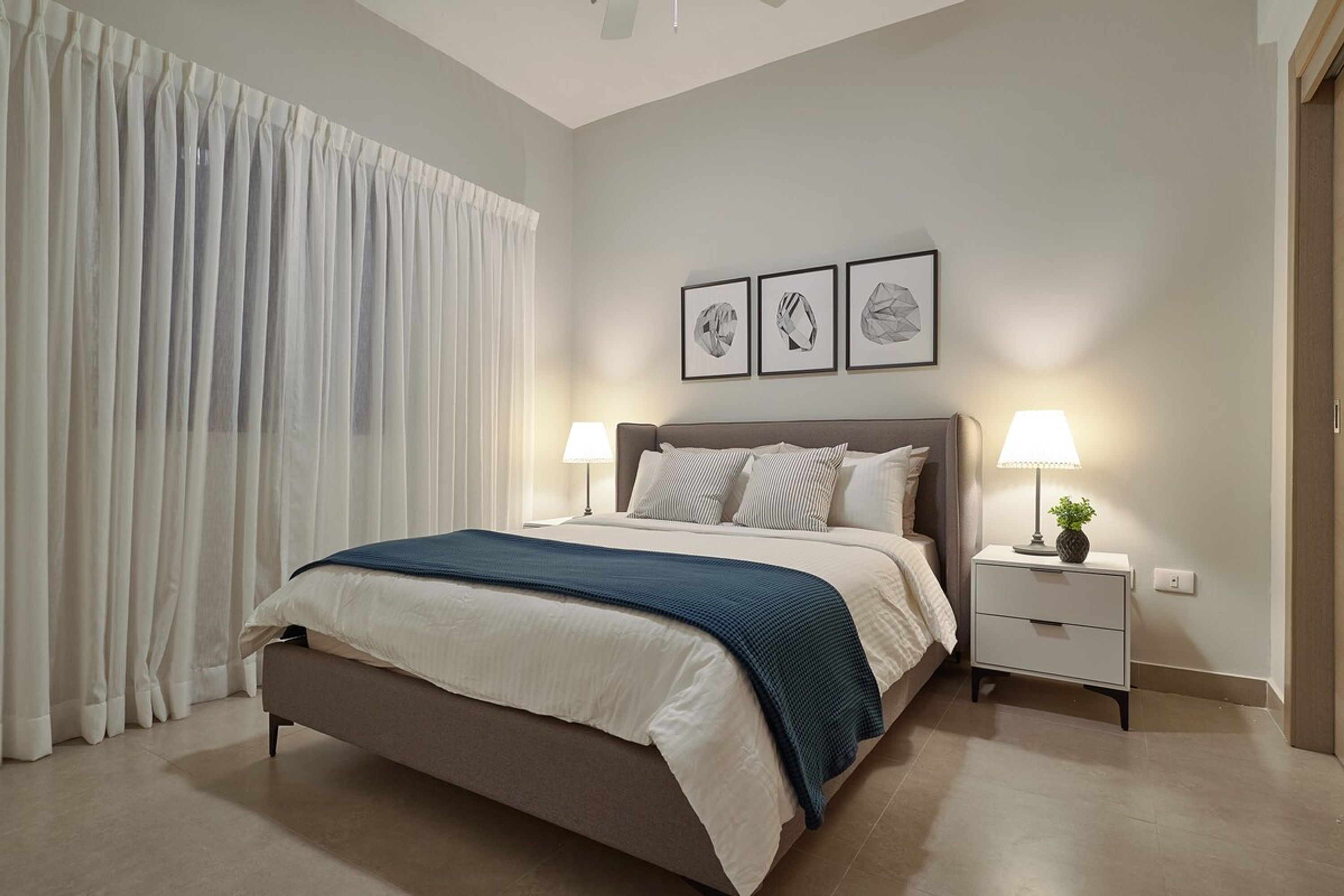 Une chambre à coucher avec un lit, des tables de chevet, une lampe et une fenêtre avec des rideaux.