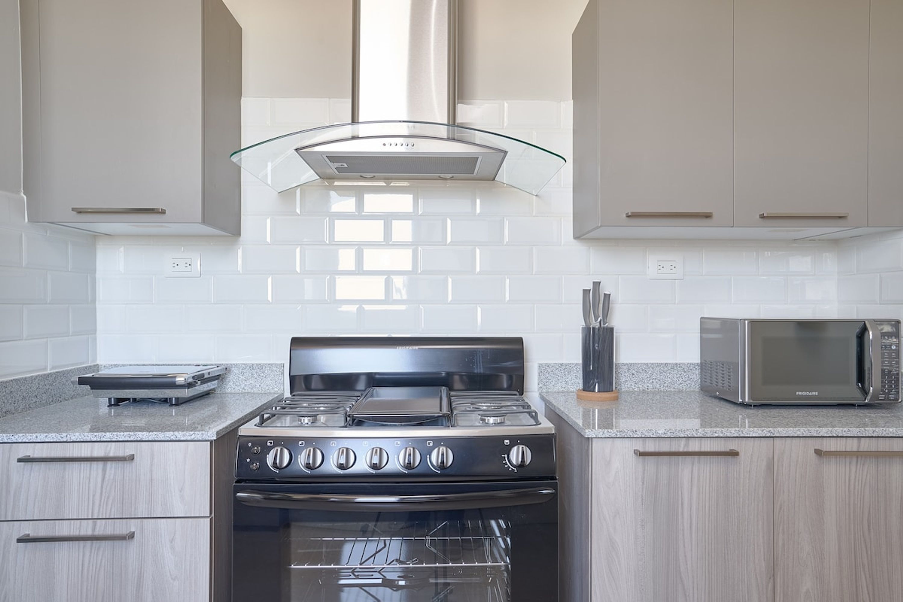 Uma cozinha com fogão, forno e micro-ondas de aço inoxidável.