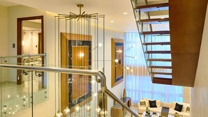 A modern interior with a glass staircase, a living area with a sofa and coffee table, and a kitchen in the background. - Acqualina s View Santo Domingo (Santo Domingo)