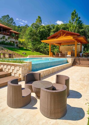 A pool area with wicker furniture and a covered seating area. - 4BR Wood Mountain Villa Jarabacoa Heated Pool (Jarabacoa)