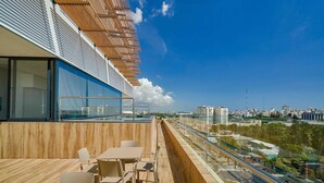 A modern outdoor balcony with a wooden floor, glass railing, and a table with chairs. - Peaceful Retreat Downtownsd Hottub Gym Family (Santo Domingo)