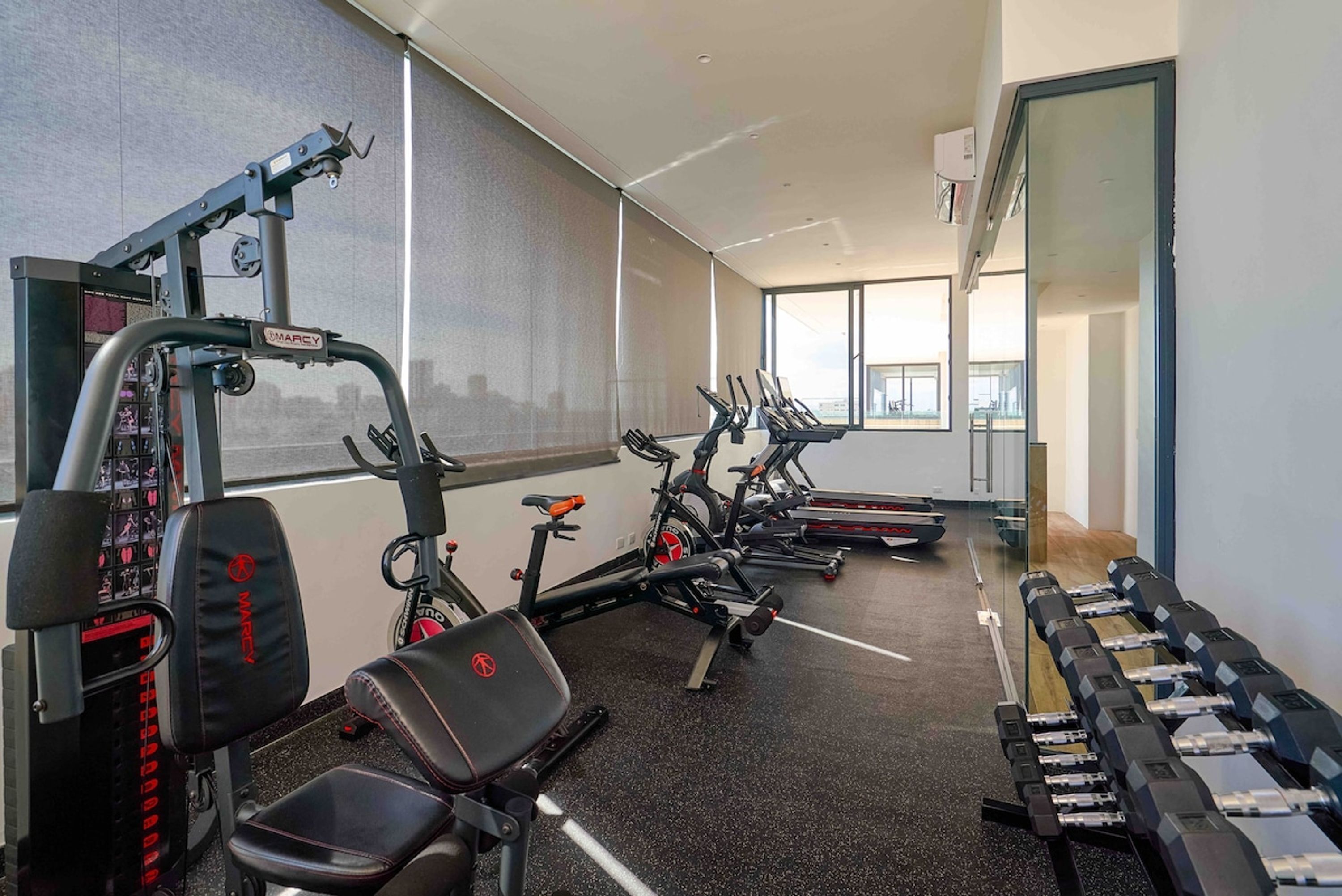 Een sportschool met cardio-apparatuur, gewichtbanken en dumbbells.