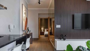 A modern hotel room with a black countertop, white chairs, a flat-screen TV, and a wooden accent wall. - LUX City Skyline Downtownsd Priv Jaccuzi Gym (Santo Domingo)