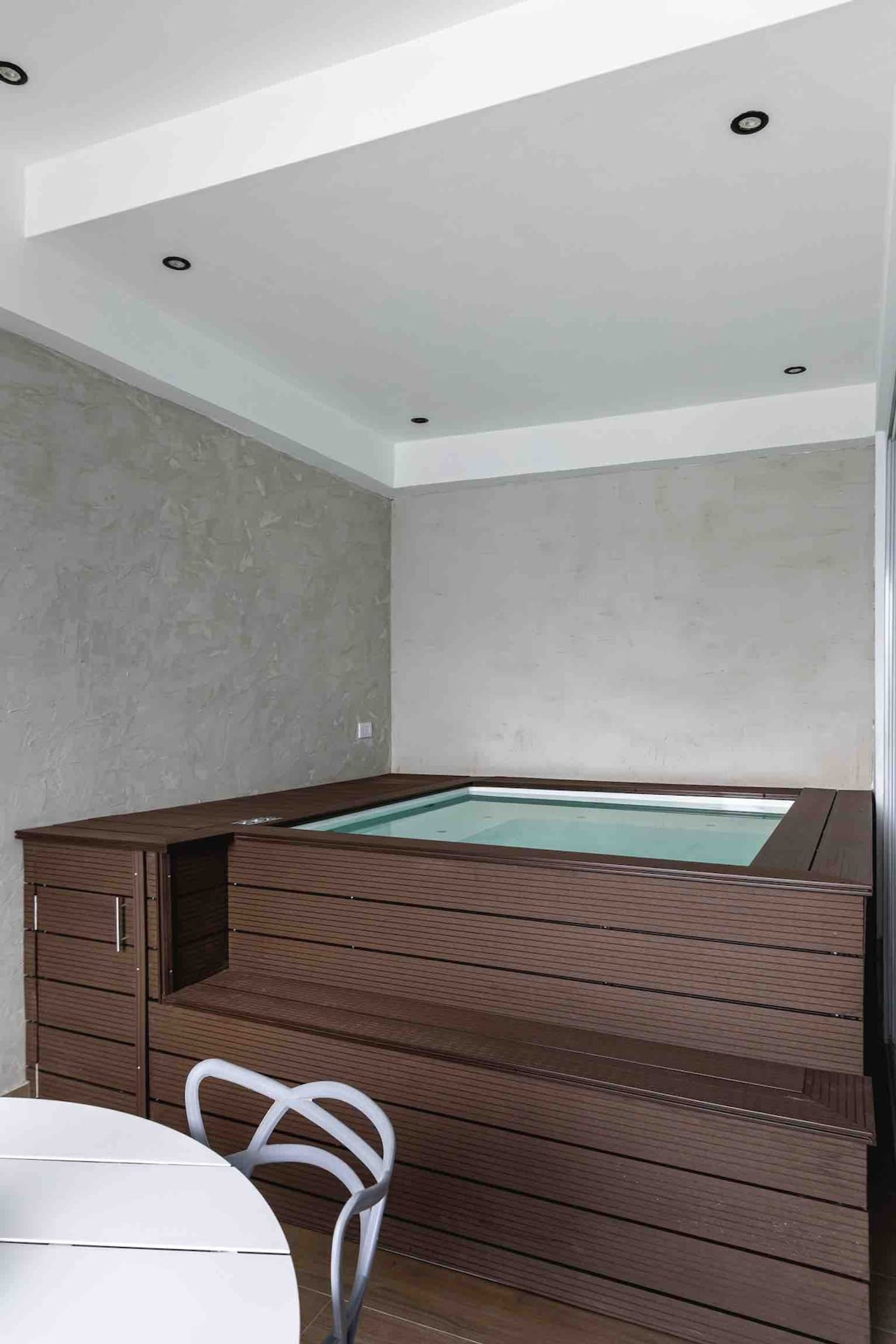 Une chambre moderne avec un bain à remous en bois, une table blanche et une chaise.