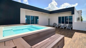 A modern outdoor pool area with a hot tub, wooden deck, and lounge chairs. - LUX City Skyline Downtownsd Priv Jaccuzi Gym (Santo Domingo)