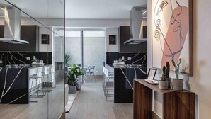 A modern kitchen with a marble island, white bar stools, and a large mirror with artwork. - LUX City Skyline Downtownsd Priv Jaccuzi Gym (Santo Domingo)