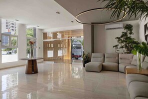 Eine moderne Lobby mit Glastisch, einer Couch und einer Topfpflanze.