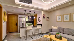 A modern kitchen with a stainless steel refrigerator, bar stools, pendant lights, and a central island. - Piantini Views Downtown SD Gym Lounge Pool (Santo Domingo)