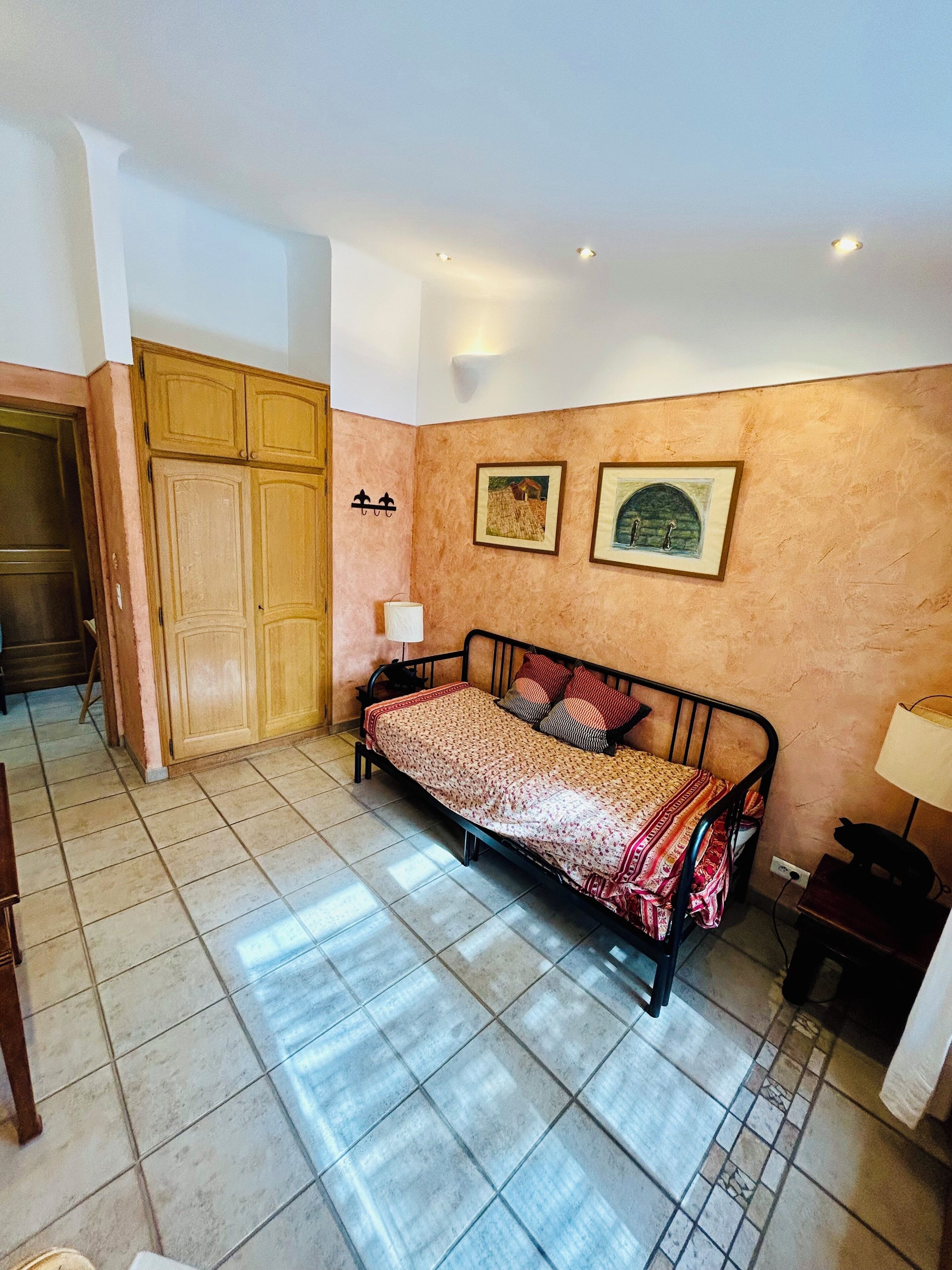 Quarto com cama, guarda-roupa, mesa de cabeceira e abajur.