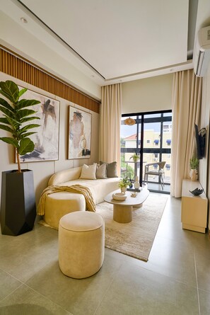Een moderne woonkamer met een bank, een poef, een salontafel en kunst aan de muur.
