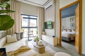 Ein modernes Hotelzimmer mit einer Couch, einem Couchtisch, einem Fernseher und einem Bett.